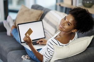 Woman sitting on couch online shopping with credit card